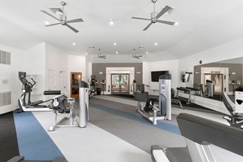 a gym with treadmills and other exercise equipment and ceiling fans at The Austin Apartment Homes, New Jersey